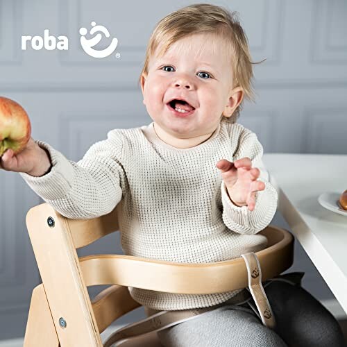 Bébé souriant dans une chaise haute tenant une pomme