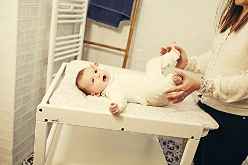 Bébé sur une table à langer avec un adulte.