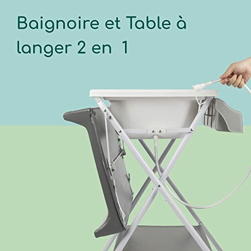 Baignoire et table à langer combinées avec main tenant un tuyau.