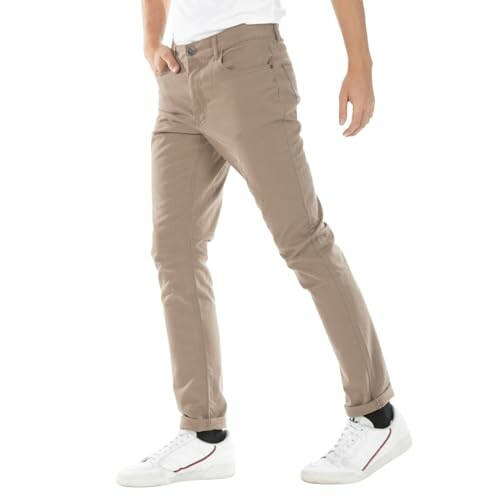 Homme portant un pantalon beige et des chaussures blanches.