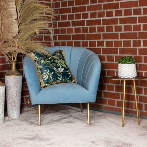 Fauteuil bleu avec coussin, mur en briques rouges, et plante sur table.