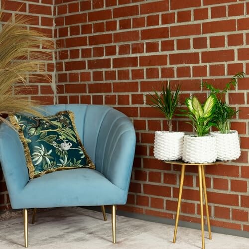 Fauteuil bleu avec coussin tropical et plantes en pot sur table.