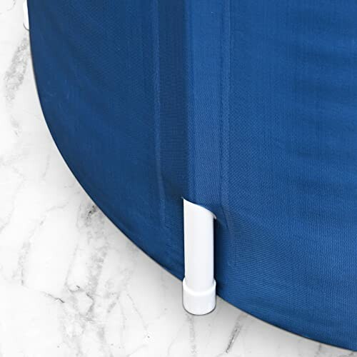 Coin d'une baignoire en tissu bleu sur un sol en marbre.