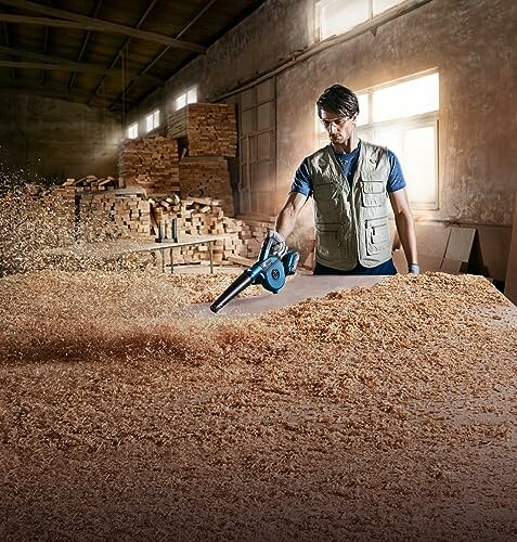 Homme nettoyant des copeaux de bois dans un atelier.