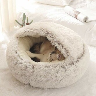 Chat endormi dans un lit en peluche blanche.