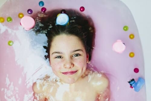 Enfant souriant dans un bain avec des jouets colorés.