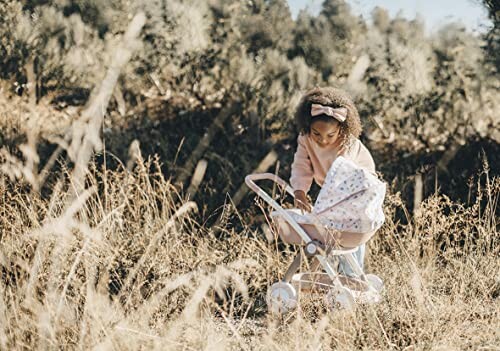 Enfant jouant avec une poussette de poupée en plein air.