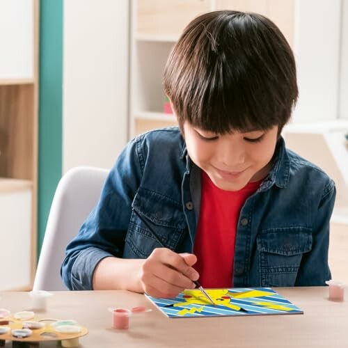 Enfant peignant une carte avec un personnage animé.