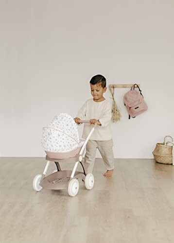 Enfant jouant avec une poussette jouet à l'intérieur.