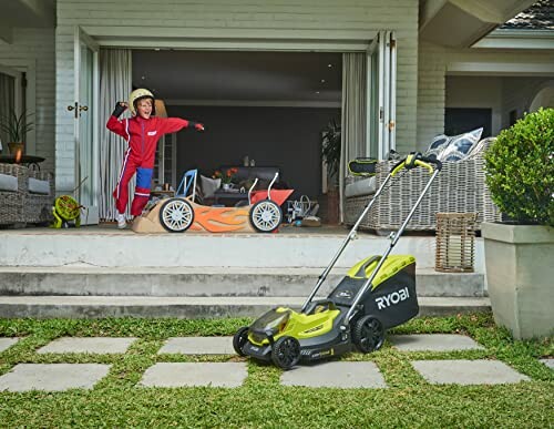 Enfant jouant avec une voiture jouet devant une tondeuse à gazon.