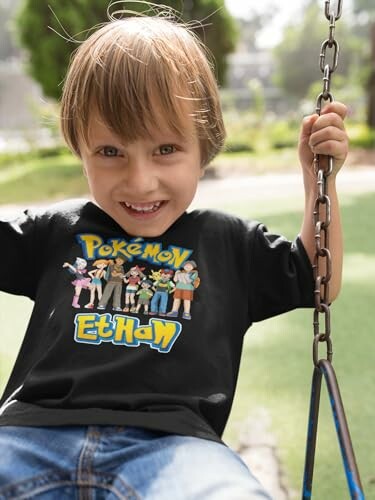 Enfant souriant sur une balançoire portant un t-shirt Pokémon.