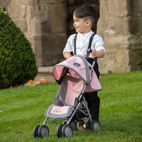 Enfant souriant avec une poussette jouet dans le jardin.