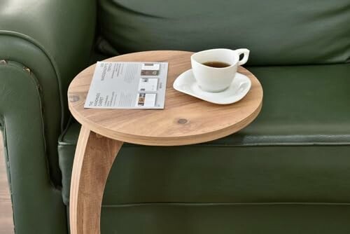 Tasse de café sur une petite table à côté d'un canapé vert.