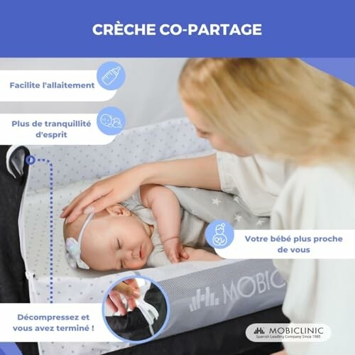 Une mère berce son bébé endormi dans un lit de crèche.