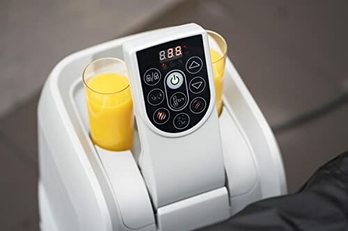 Massager électrique pour les pieds avec deux verres de jus d'orange.