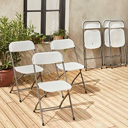 Chaises pliantes blanches sur une terrasse en bois.