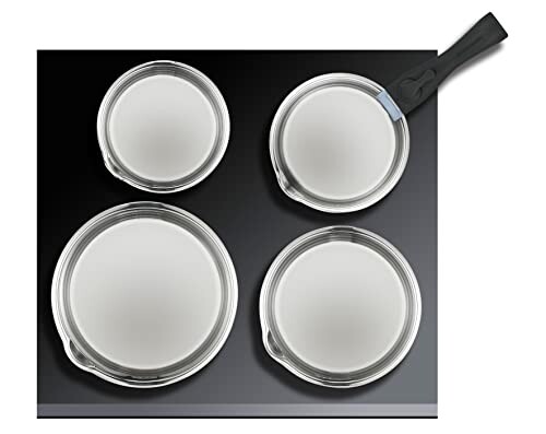 Quatre casseroles sur une plaque de cuisson en verre.