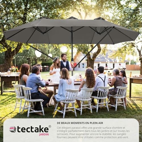 Groupe de personnes à une fête en plein air avec un grand parasol.