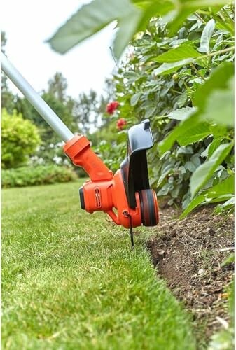 Taille-bordure orange en action dans un jardin