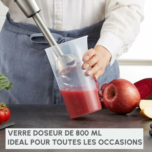 Personne utilisant un mixeur plongeant dans un verre doseur.