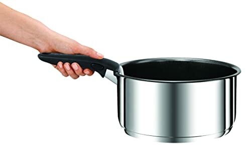 Main tenant une casserole en acier inoxydable.