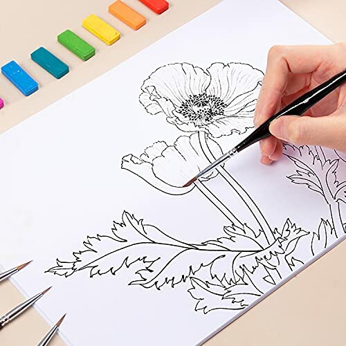 Main dessinant des fleurs avec des pastels colorés.