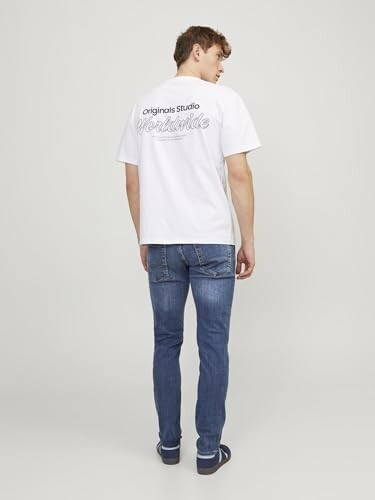 Homme de dos portant un t-shirt blanc et un jean bleu