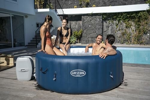 Quatre personnes discutent dans un spa gonflable près d'une piscine.