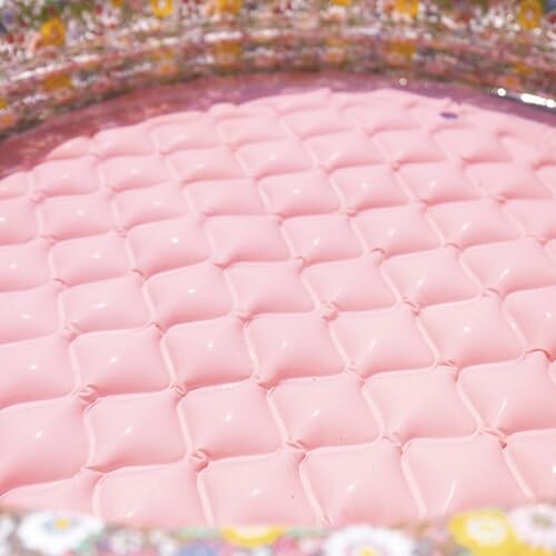 Intérieur d'une piscine gonflable rose avec motif floral.