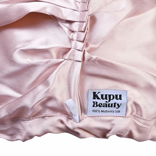 Taie d'oreiller en soie rose avec étiquette Kupu Beauty.