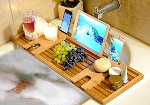 Plateau de bain en bois avec tablette, téléphone, raisin et verre de vin.