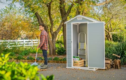 Homme balayant près d'un abri de jardin en plein air.