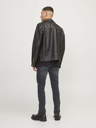 Homme portant une veste en cuir noir vu de dos.