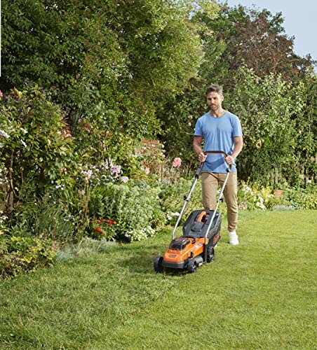 Homme tondant la pelouse dans un jardin fleuri.