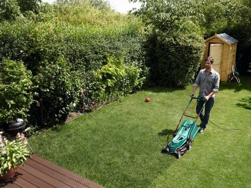 Homme tondant la pelouse dans un jardin.