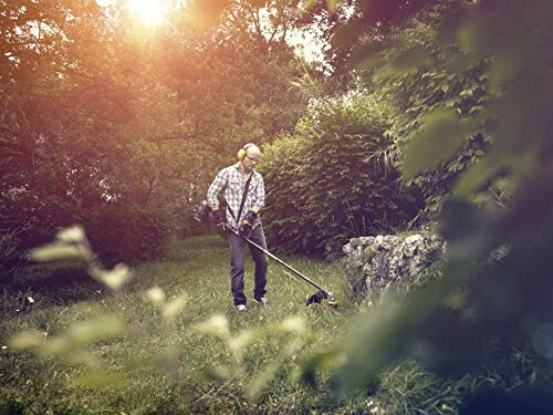 Homme utilisant un coupe-bordures dans un jardin ensoleillé.