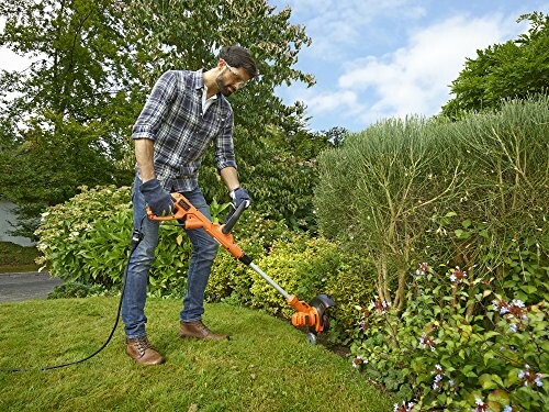 Homme utilisant une tondeuse électrique dans le jardin.