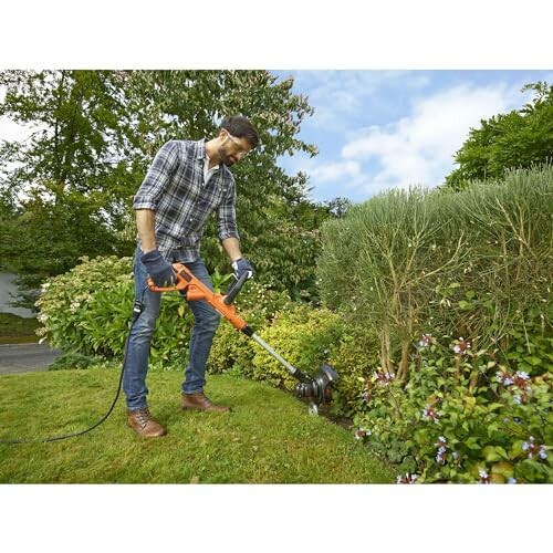 Homme utilisant un coupe-bordure électrique dans le jardin.