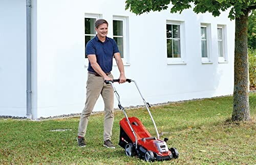 Homme utilisant une tondeuse à gazon rouge devant une maison blanche.