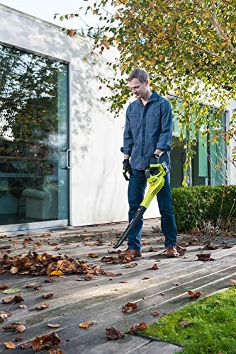 Homme utilisant un souffleur de feuilles sur une terrasse.