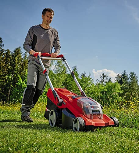 Homme utilisant une tondeuse à gazon rouge sur l'herbe verte.