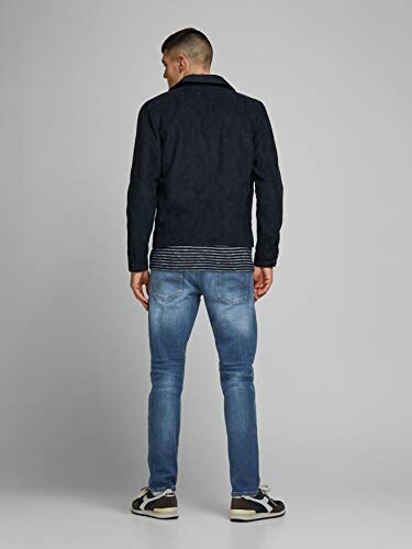 Homme portant une veste noire et un jean bleu, vu de dos.