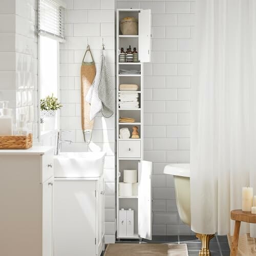 Salle de bain moderne avec armoire de rangement blanche et baignoire.