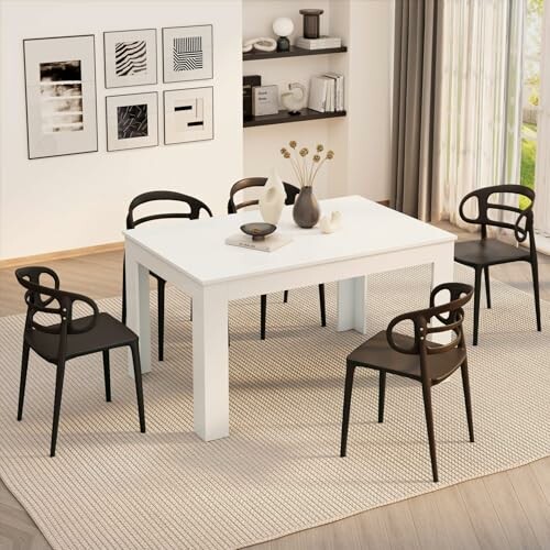 Salle à manger moderne avec table blanche et chaises noires.