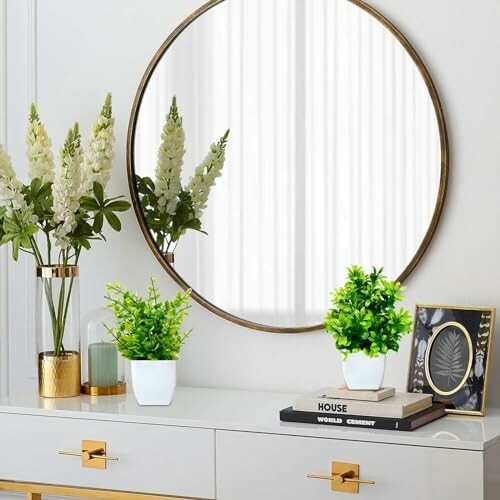 Miroir rond avec décoration de plantes sur une commode.