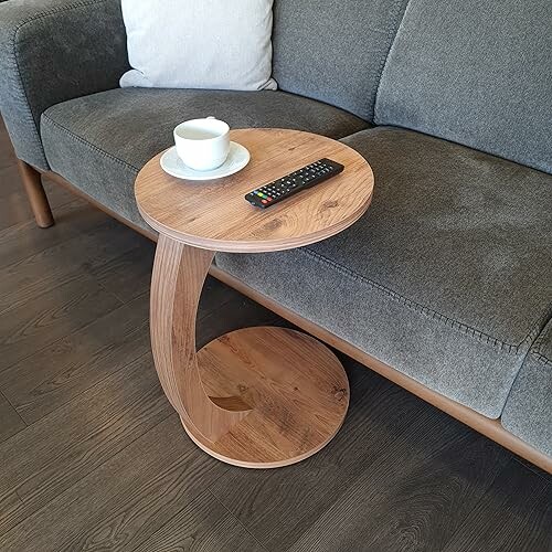 Petite table d'appoint en bois avec tasse et télécommande sur un canapé.