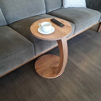 Table d'appoint en bois moderne avec tasse et télécommande.