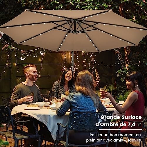 Groupe d'amis dînant sous un grand parasol avec des lumières.