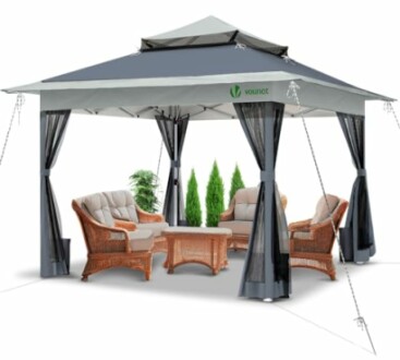 Tonnelle de jardin avec meubles en osier et rideaux.