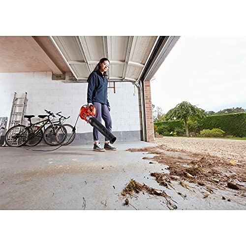 Personne utilisant un souffleur de feuilles dans un garage.